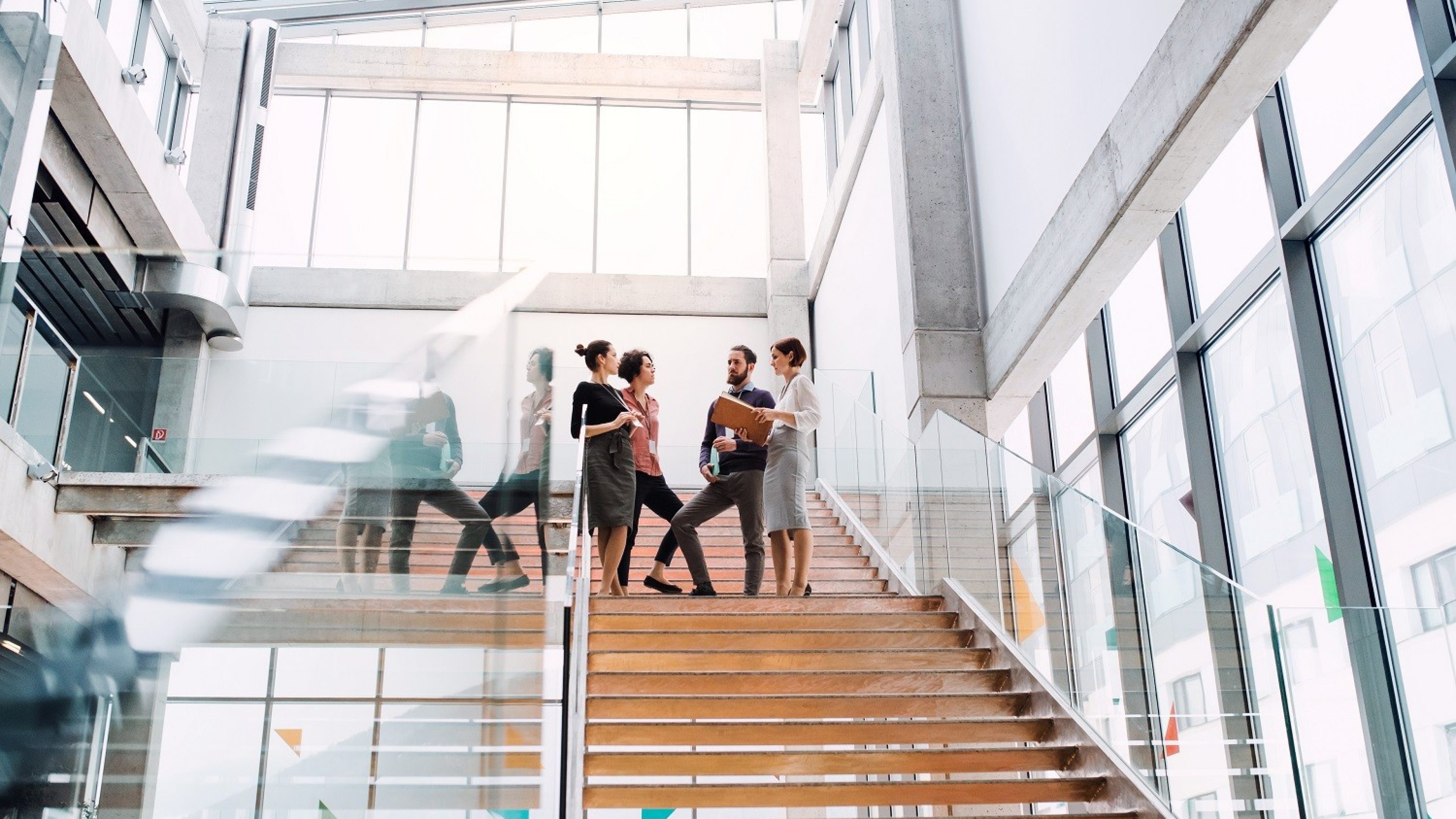A group of young businesspeople standing on a staircase, talking.