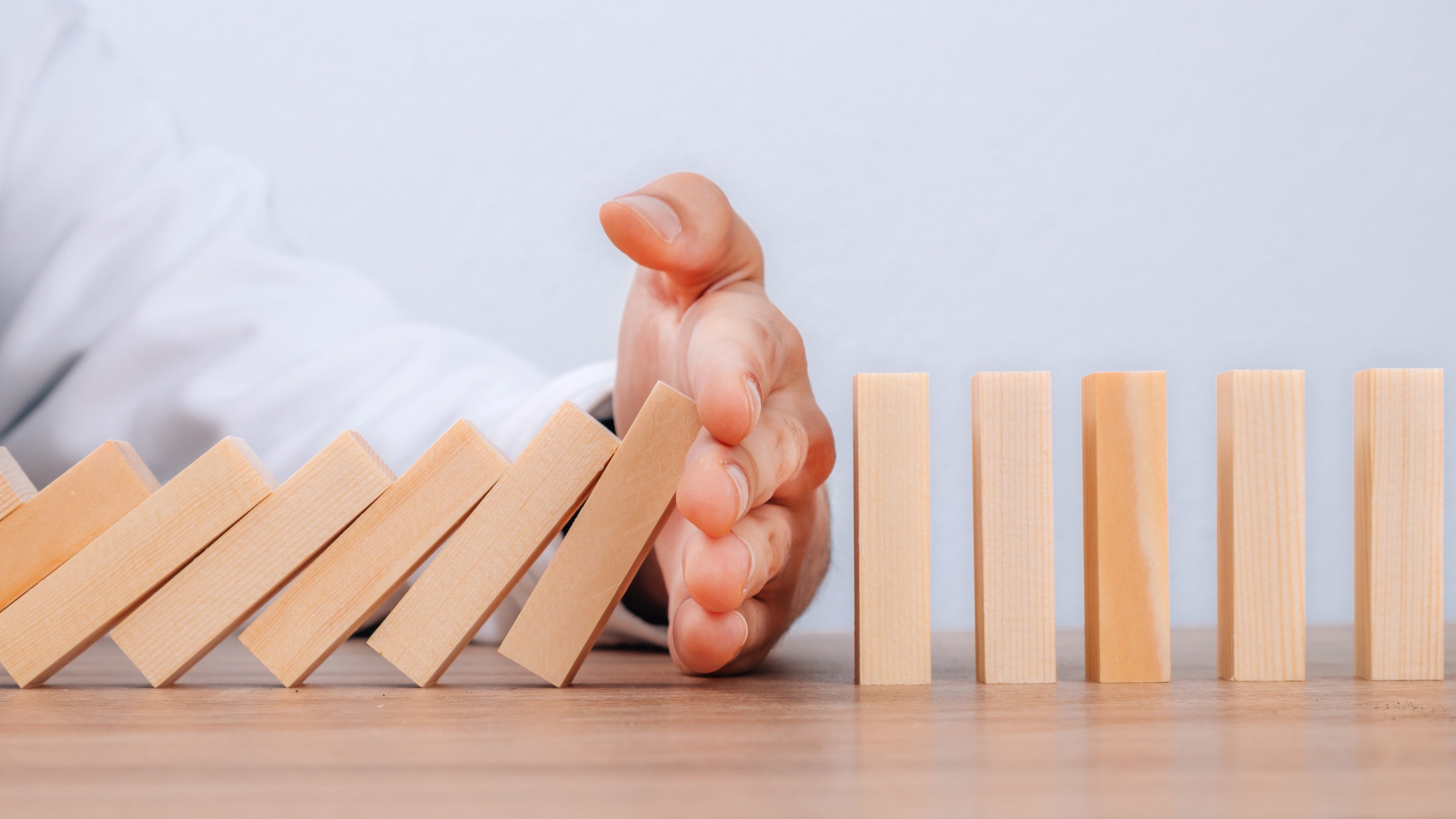 hand controlling domino effect pollution, business concept