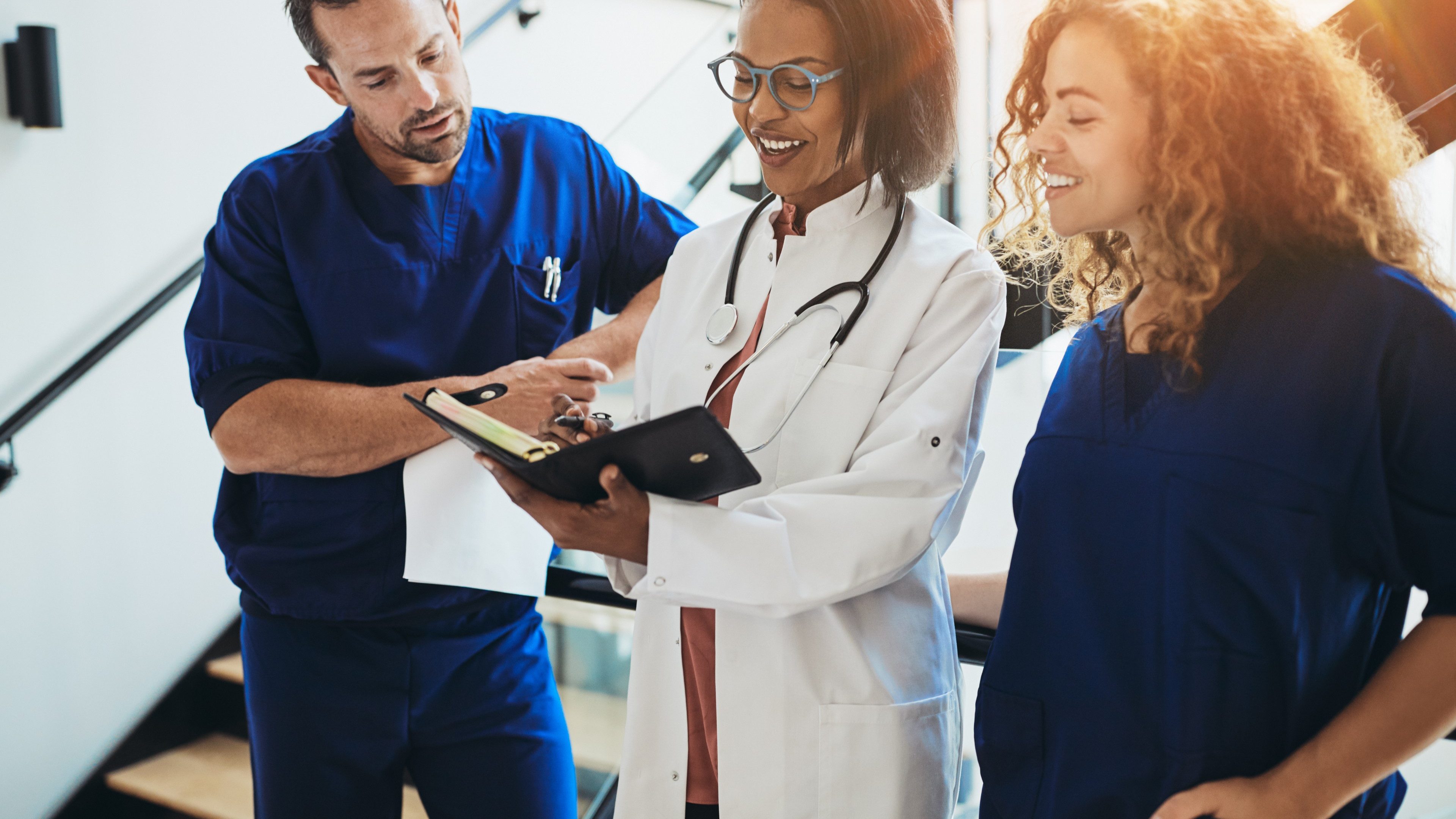 Diverse group of smiling doctors standing together in a hospital corridor discussing a patient's dignosis