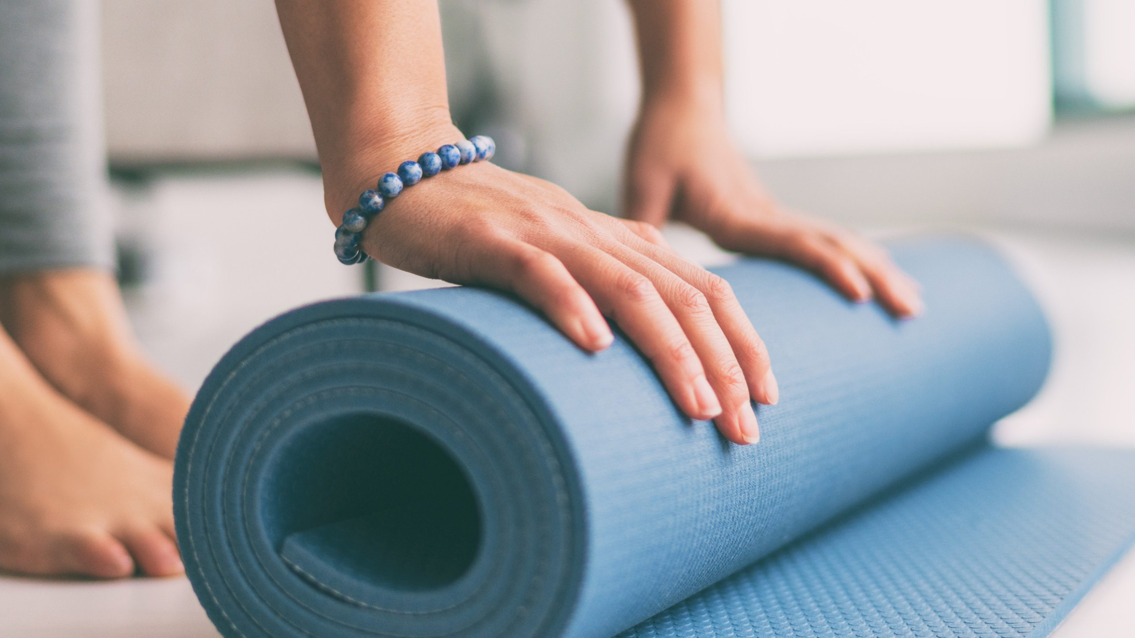 Yoga at home active lifestyle woman rolling exercise mat in living room for morning meditation yoga banner background.