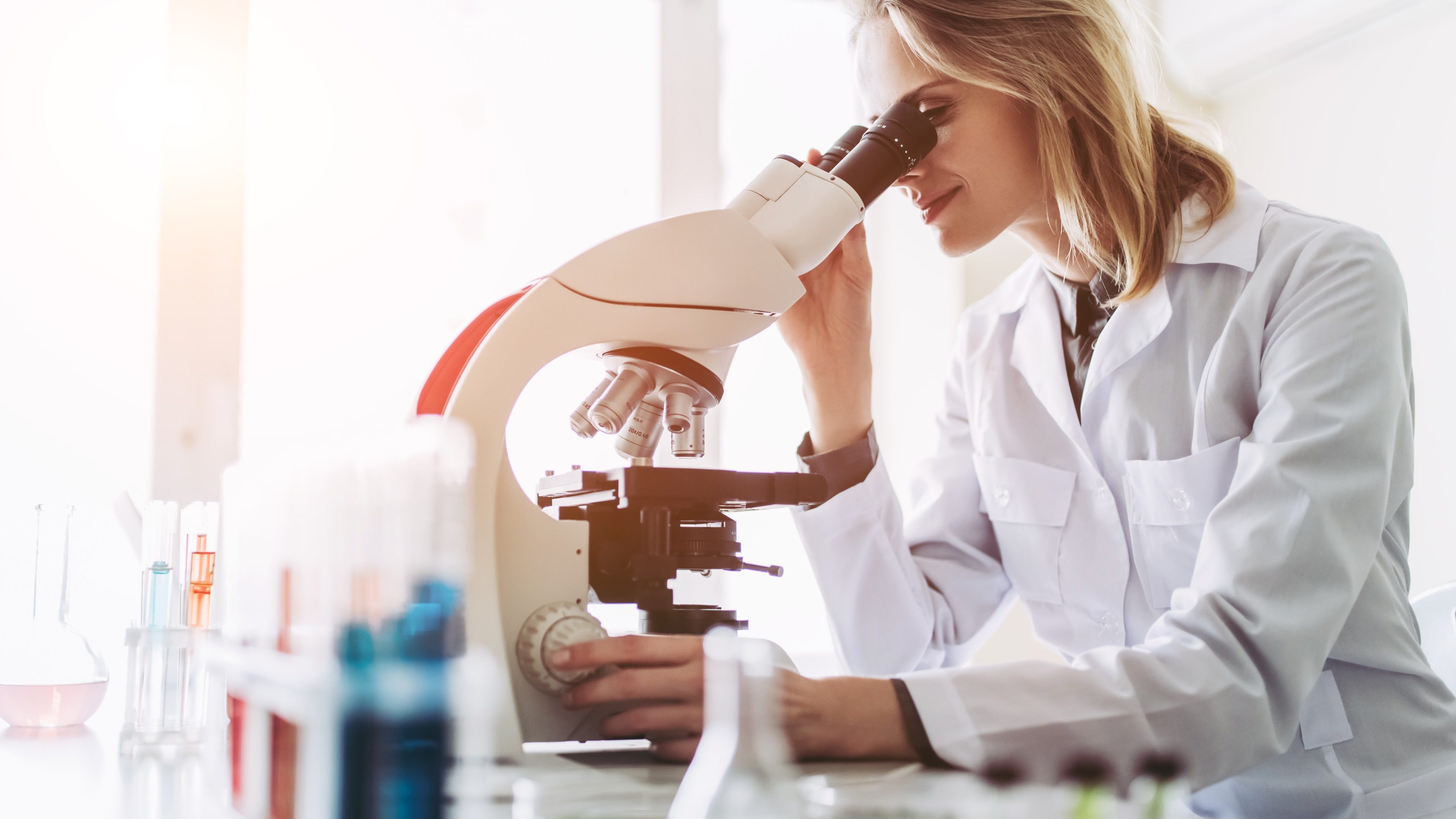 Experienced female scientist is working in laboratory. Doing investigations with microscope.
