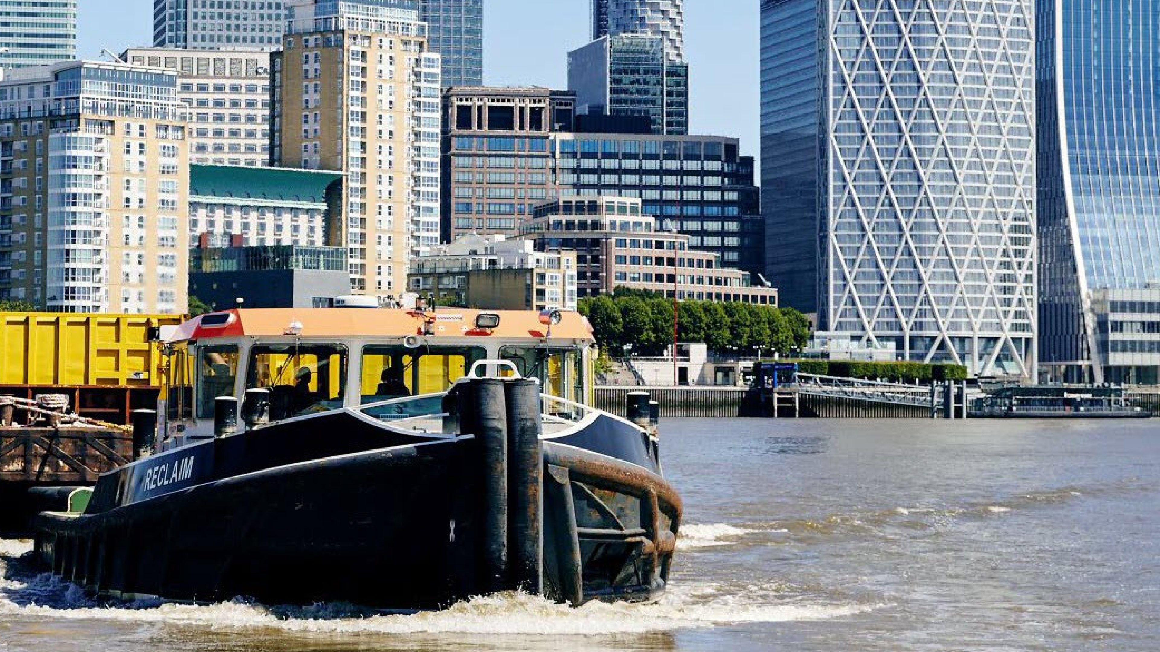 A tug on the Thames near Charlton with a view of a skyline.