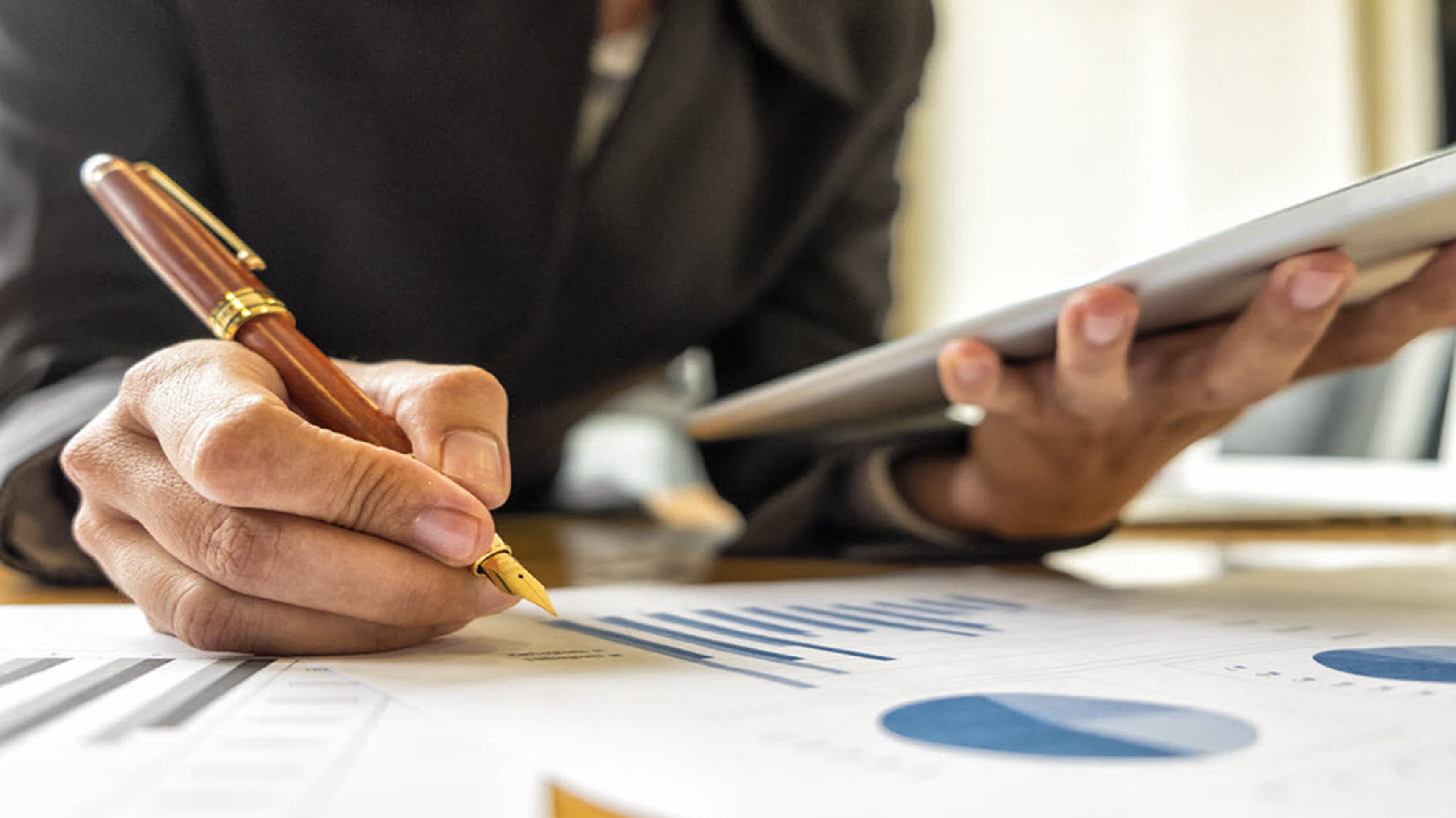 A person holding a pen in one hand and a tray in the other. In front of her are government bond graphics.