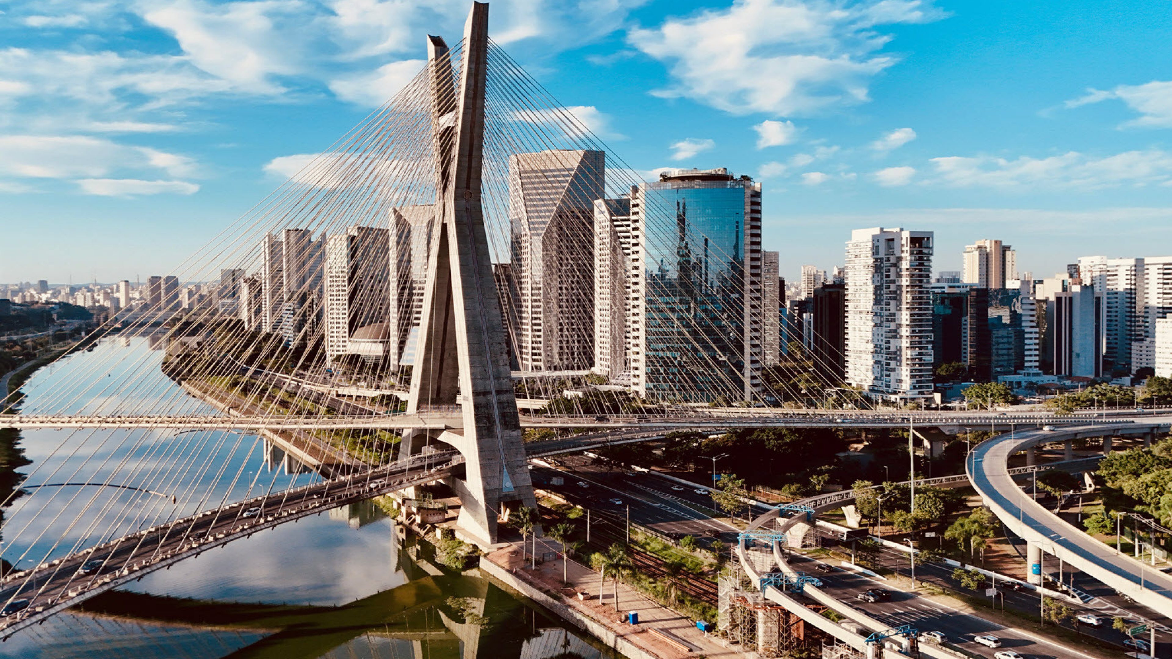 The photo shows the elegant cable-stayed bridge Ponte Estaiada in Sao Paulo, which rises strikingly above the Rio Pinheiros against the modern skyline.