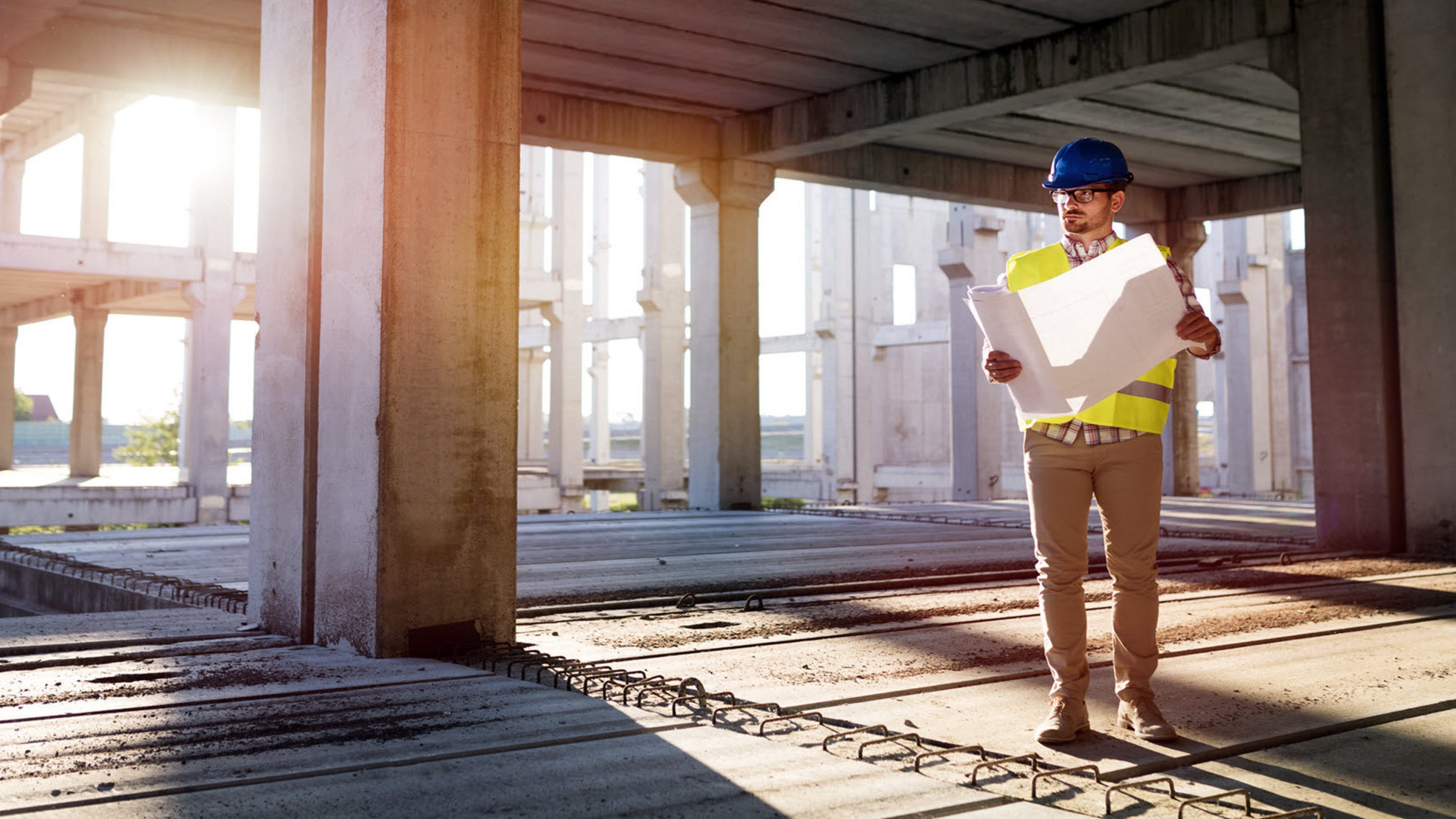 Un homme sur un chantier, un plan de construction à la main.
