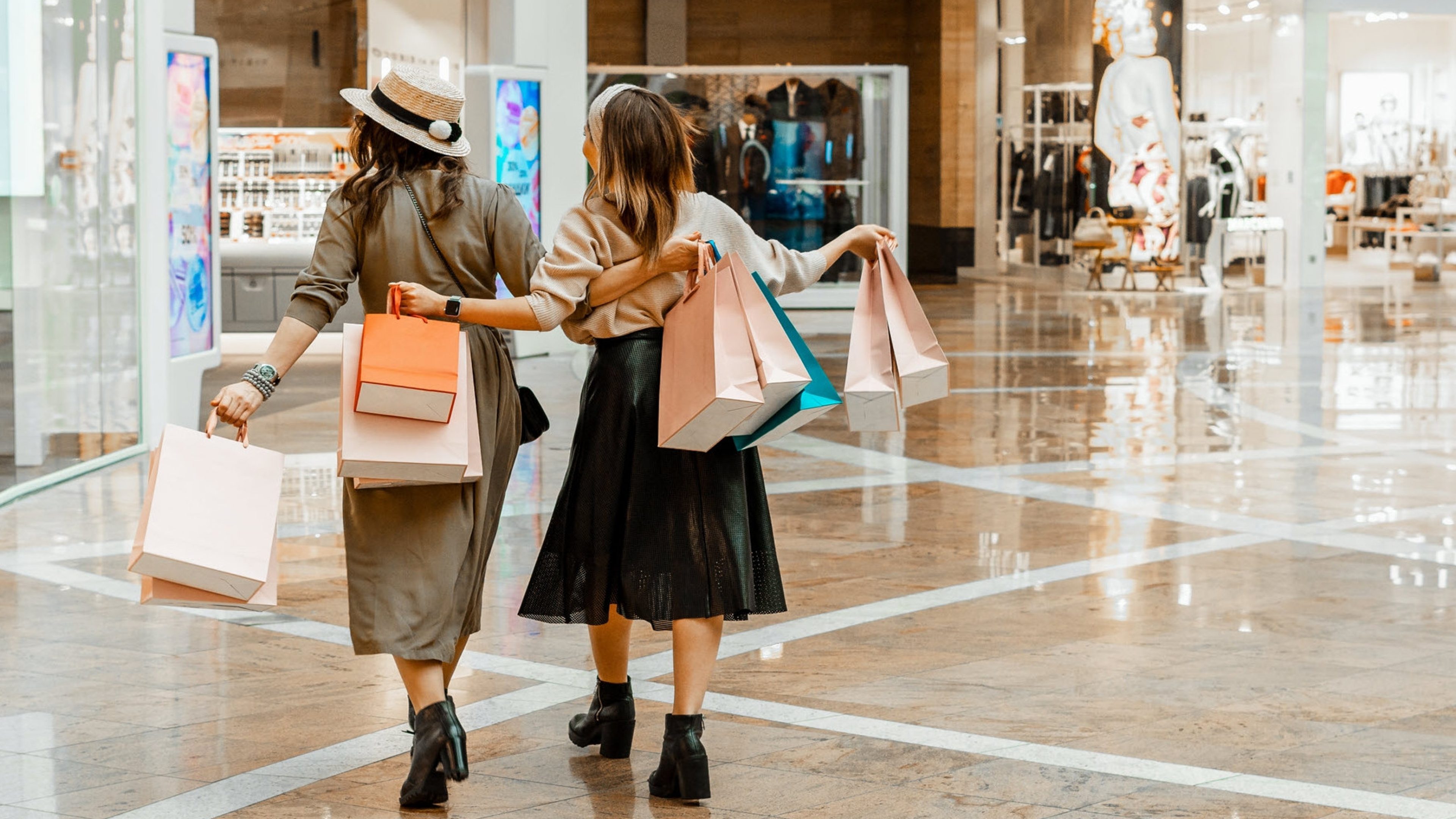 Deux femmes avec des sacs de courses à la main dans un centre commercial.