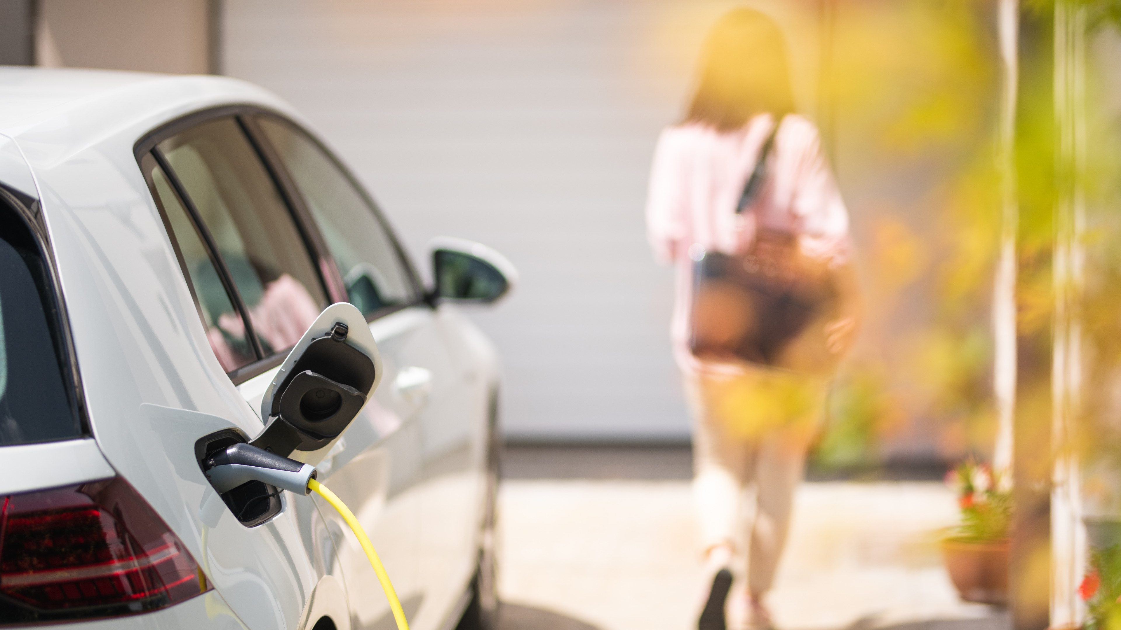 Close up of a electric car charger with female silhouette in the background